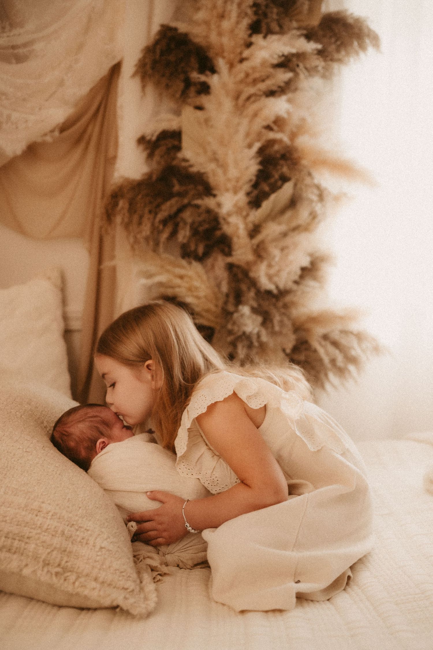 A series of intimate lifestyle portraits showing tender moments between parent and child on cream colored bedding.