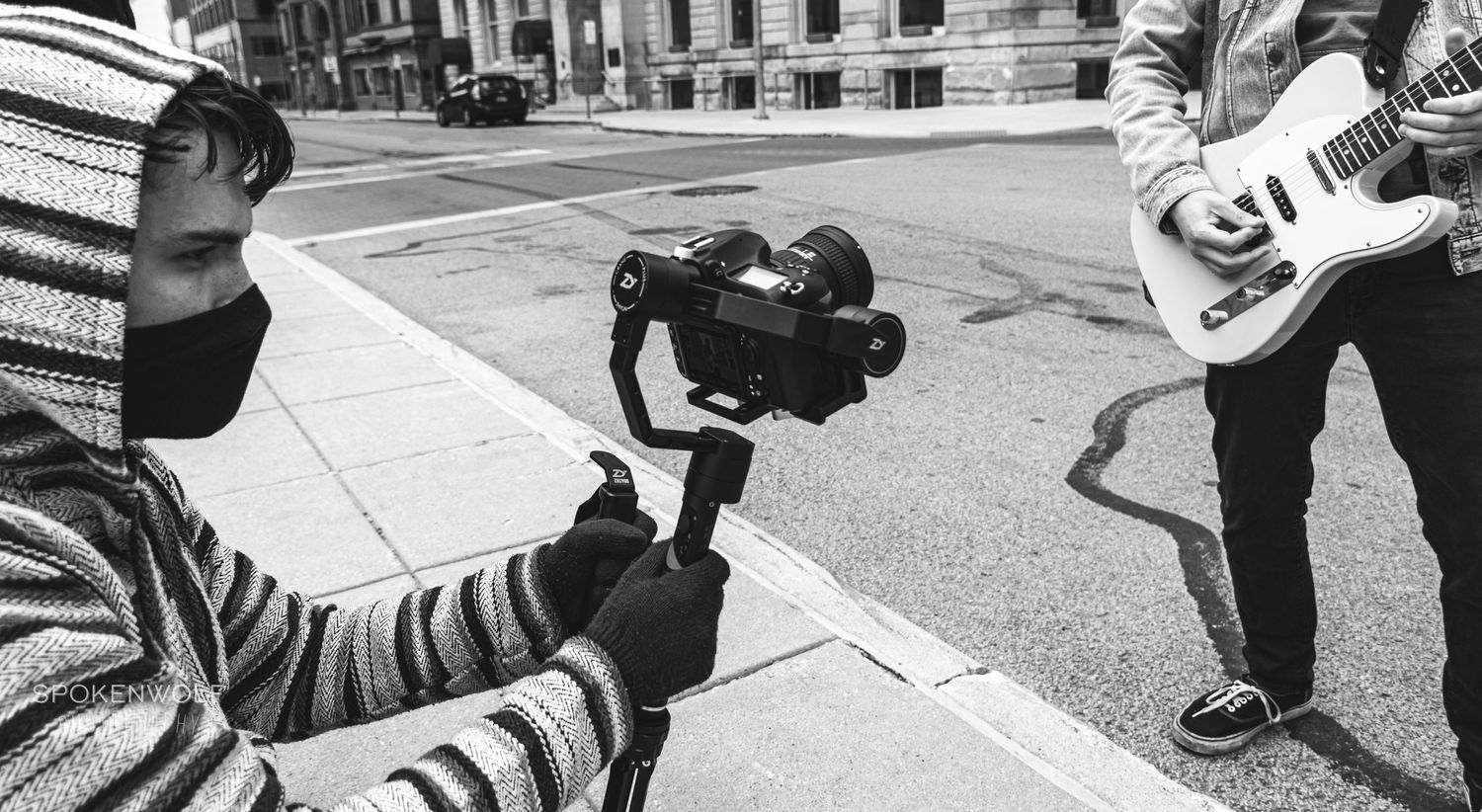 Person filming on a city street with a handheld camera gimbal stabilizer.