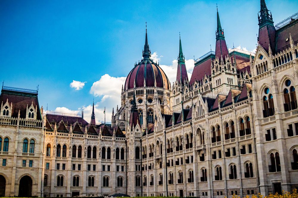 Gothic spires and ornate facade of the Hungarian Parliament Building against blue sky.