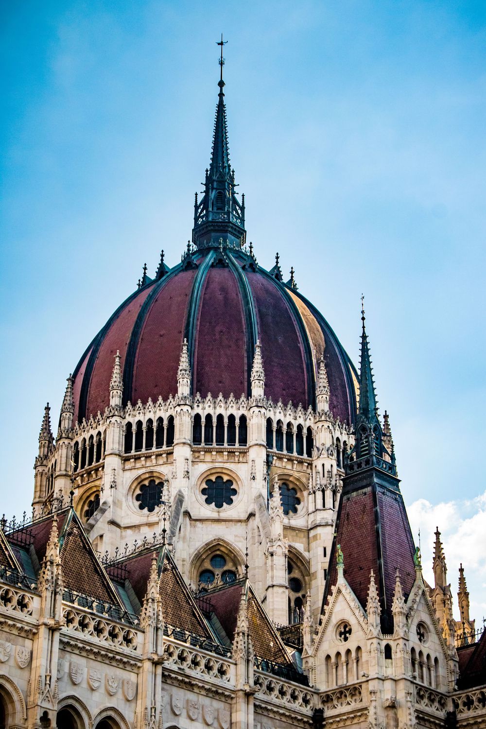 Intricate Gothic dome of the Hungarian Parliament building featuring ornate spires and burgundy roof.