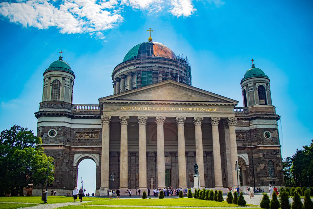 Majestic neoclassical basilica with large dome and columns under blue sky.