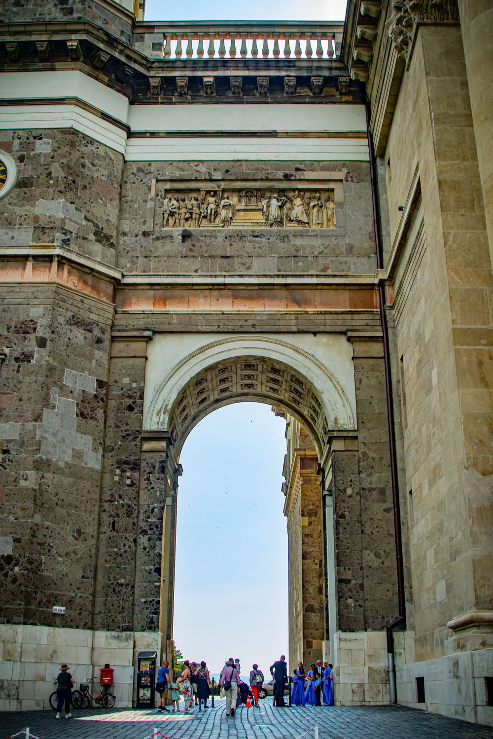 Ancient stone archway entrance with decorative reliefs and visitors gathering below.