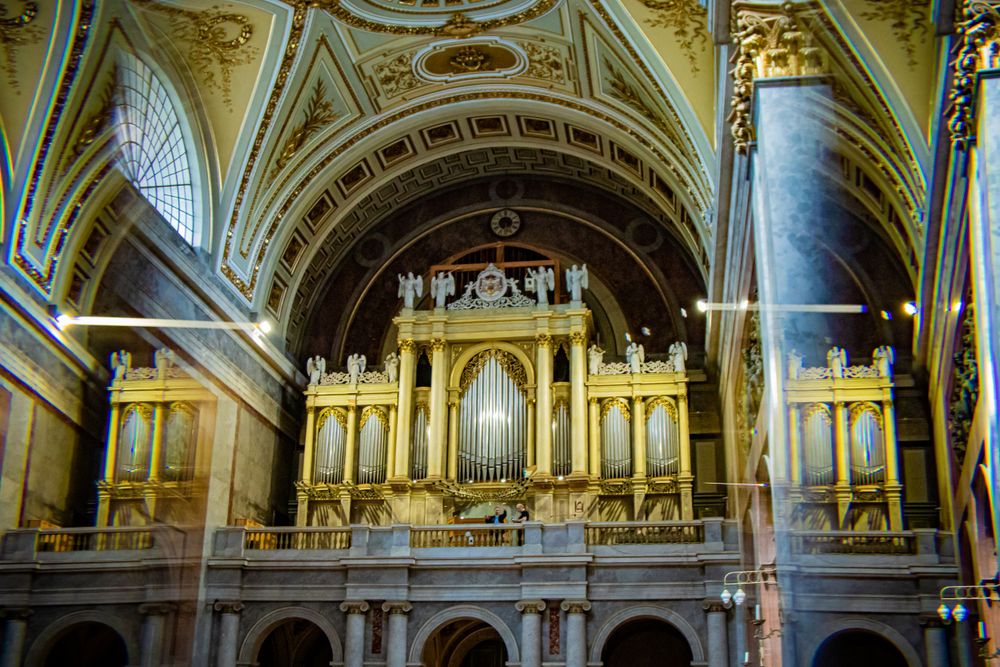 Magnificent golden pipe organ with ornate architectural details inside a historic cathedral.
