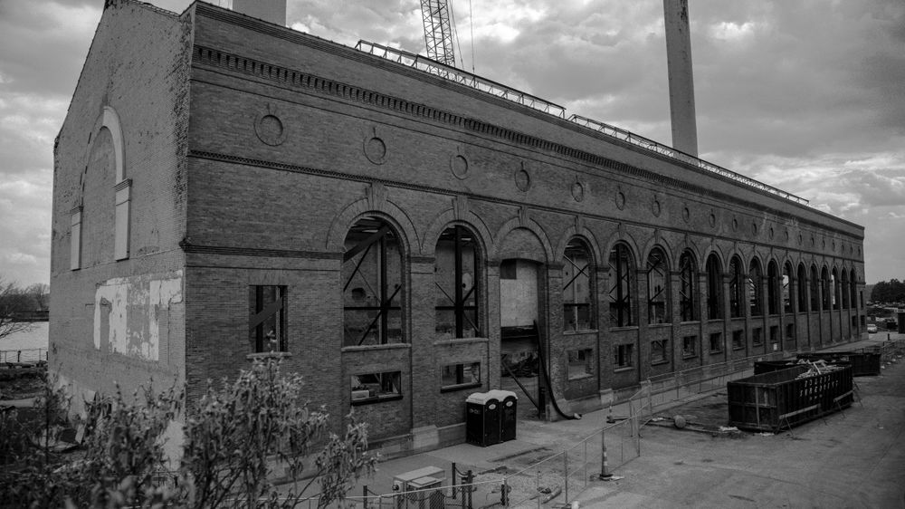 Historic brick industrial building with arched windows photographed in black and white.