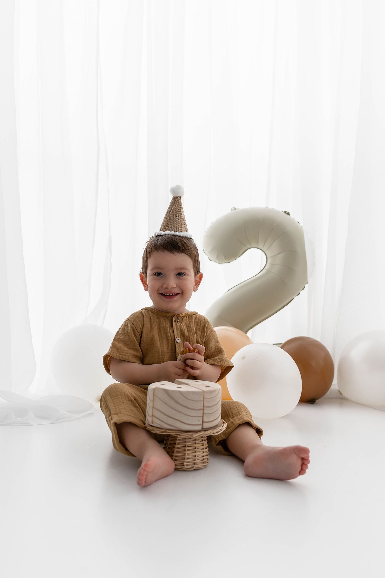 Happy child in party hat with number 2 balloon and birthday cake.