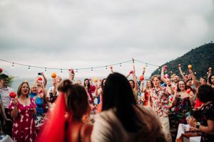 Outdoor celebration at dusk with string lights and colorful lanterns hanging above a festive crowd on a mountaintop.
