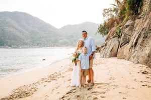 A romantic beachside moment with mountain views and rocky cliffs along a sandy shore at sunset.