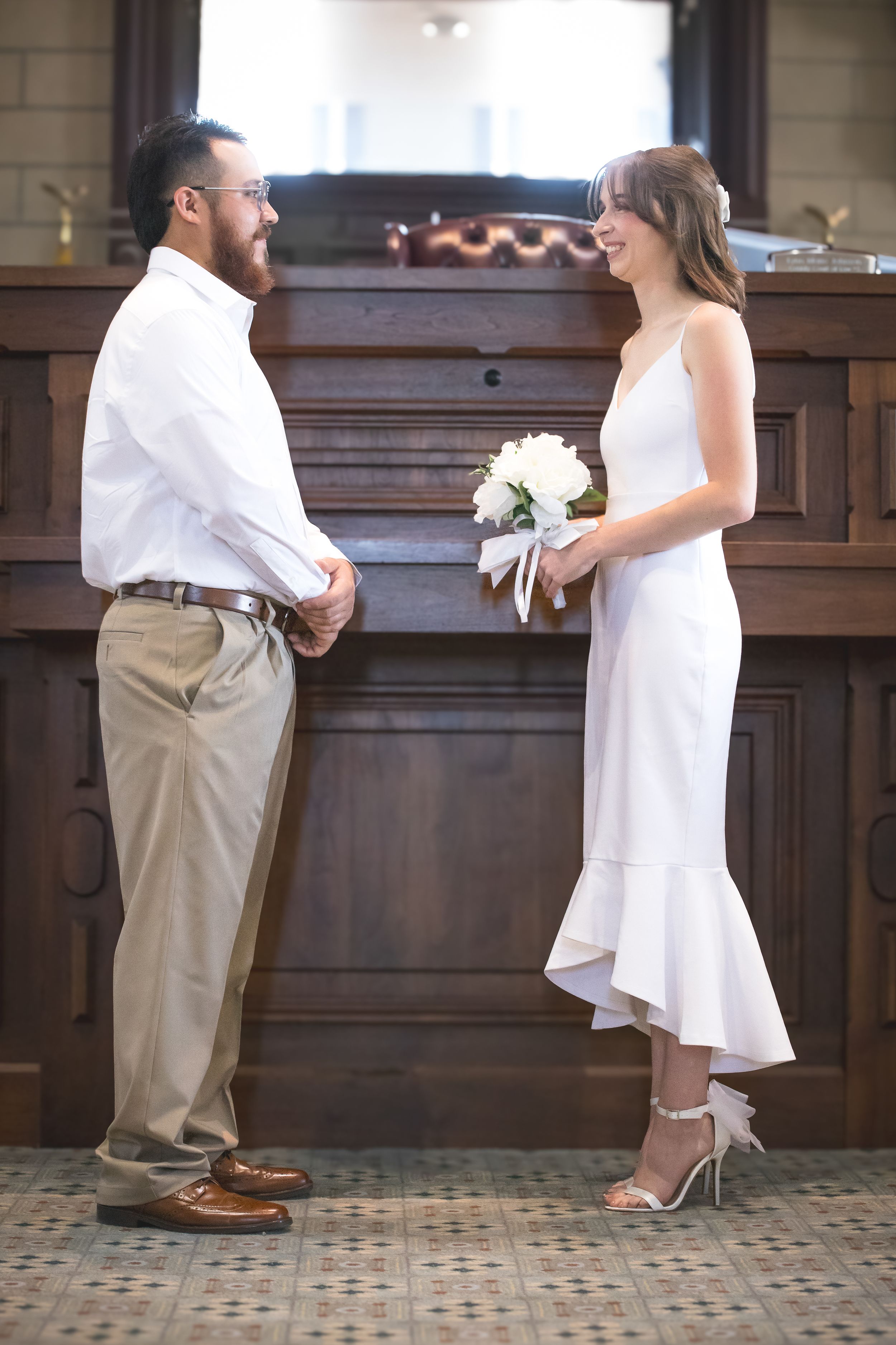 Wedding ceremony sequence showing white dress and khaki pants against wooden paneled backdrop.
