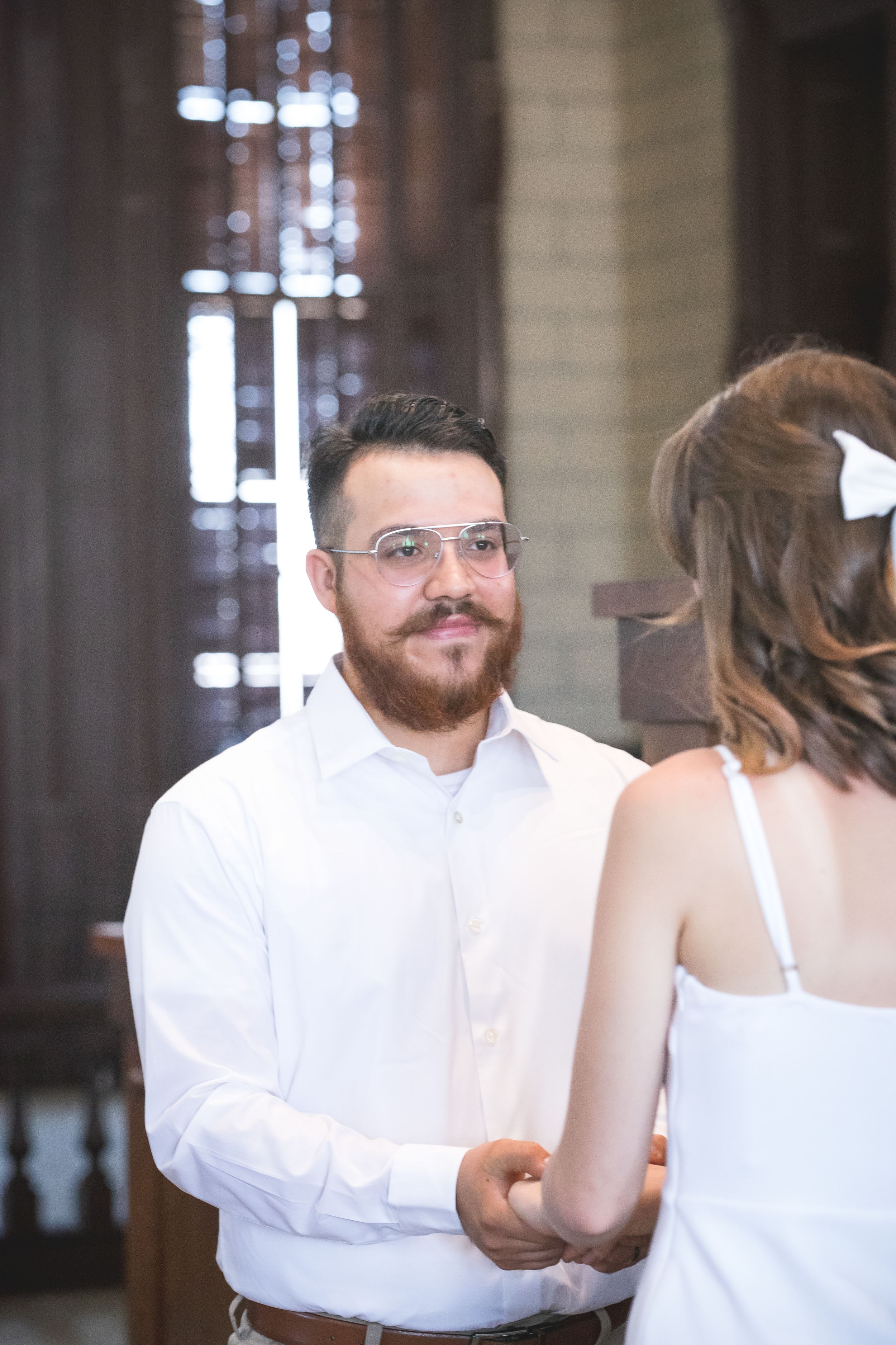 Indoor wedding ceremony sequence with white attire against dark wood paneling.
