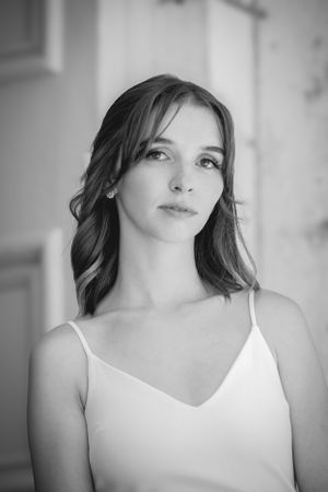 A portrait of someone in a white dress against a light background.