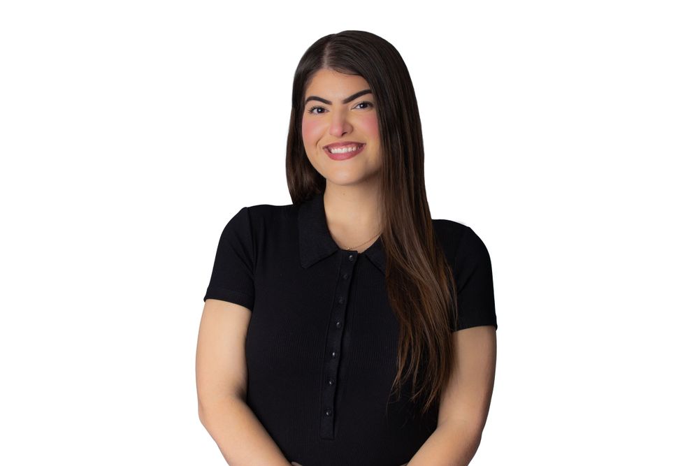 Professional studio portrait of a woman in black top with long dark hair against white background.