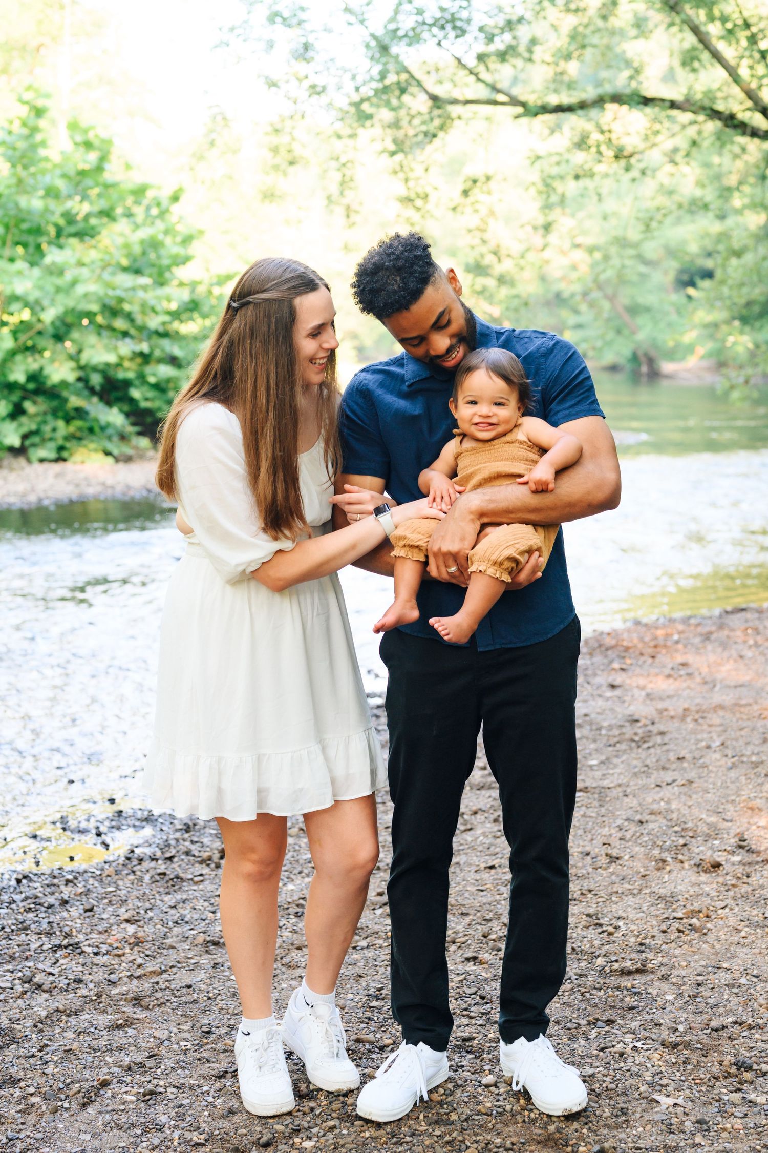 A family enjoying a sunny day by a creek in a lush green park setting.