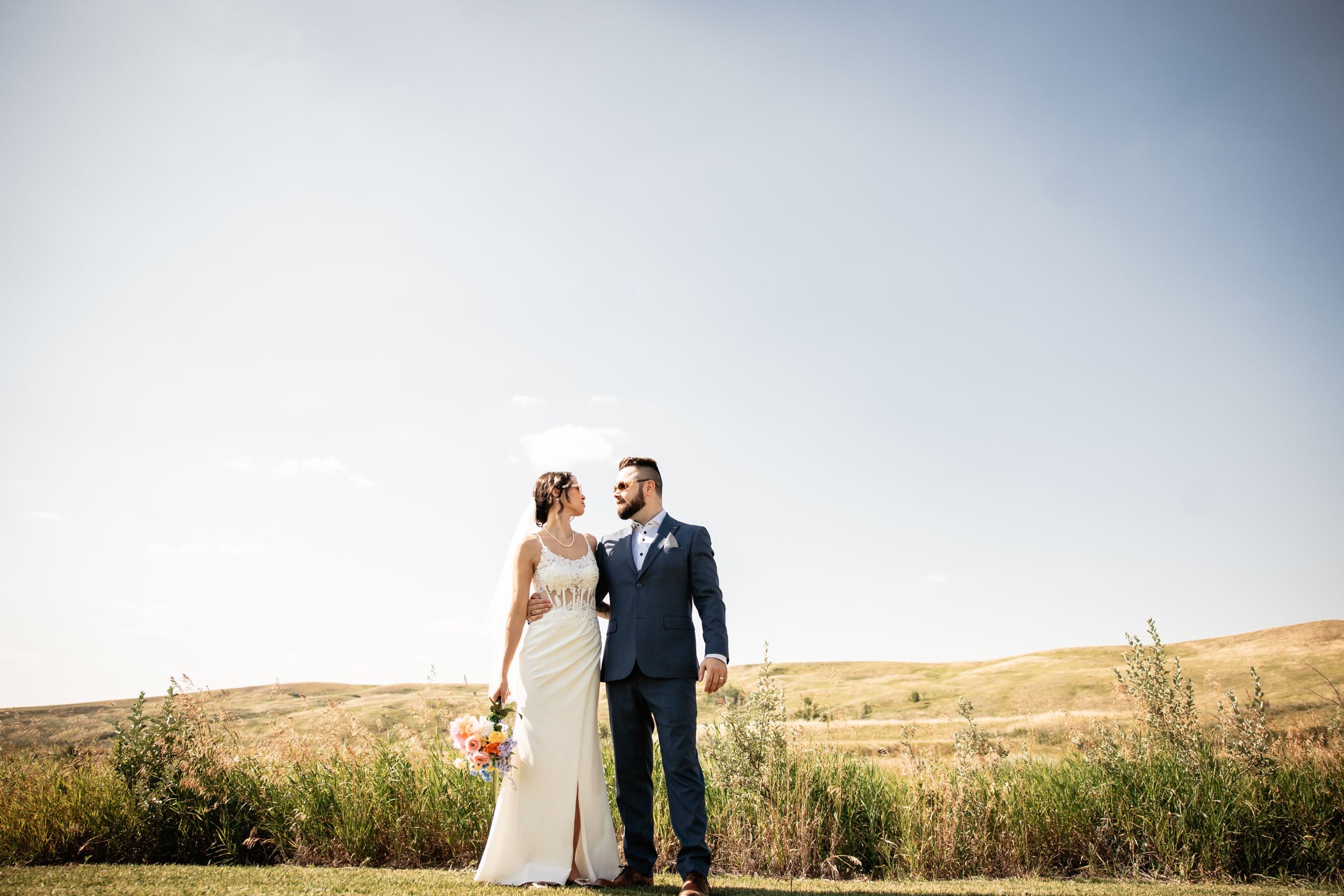 Bride and Groom looking at each-other with a wide sky in the background