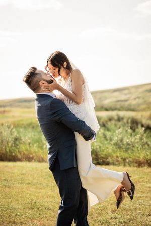 Groom picking up bride and kissing