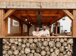 Couple looking right at the camera, standing by a wooden gazebo