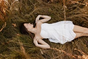 Person lying in tall grass during golden hour creating dreamy outdoor portraits.