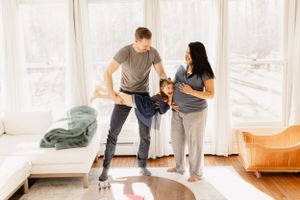 Playful couple interaction in bright, sunlit room with white decor.