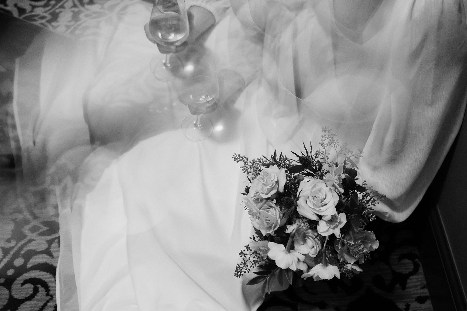 Black and white close-up of a wedding bouquet with roses and mixed flowers.