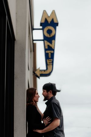 Couple sharing an intimate moment beneath a vintage motel sign.
