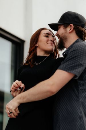Romantic couple embracing and smiling while standing together in casual attire.