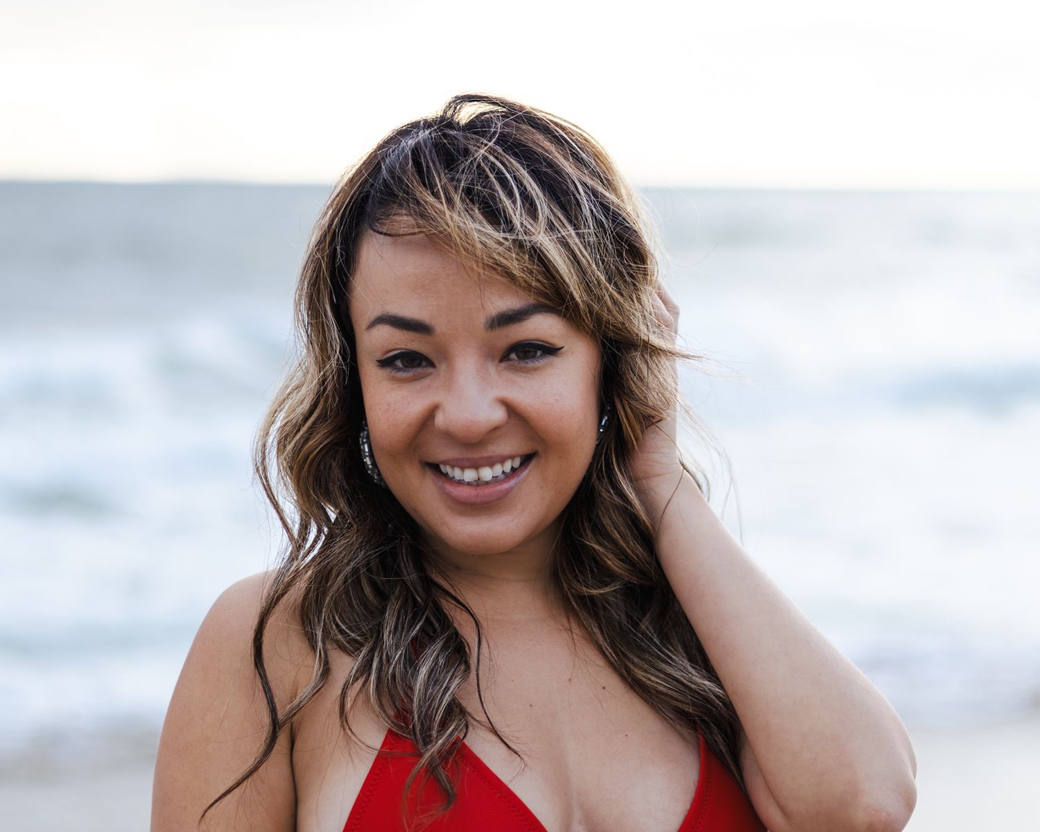 Beach photoshoot with waves and cloudy sky in background.