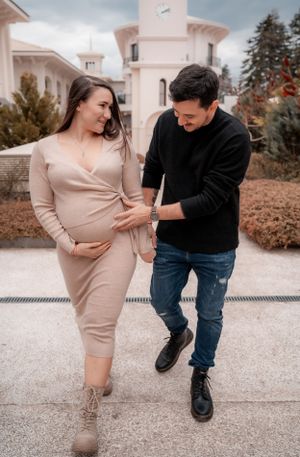 Joyful couple in casual attire walking together on pathway with elegant architecture in background.