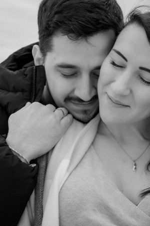 Black and white portrait of a couple in a tender embrace with peaceful expressions.