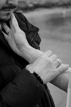 Close-up black and white photo of hands tenderly embracing during an intimate moment.