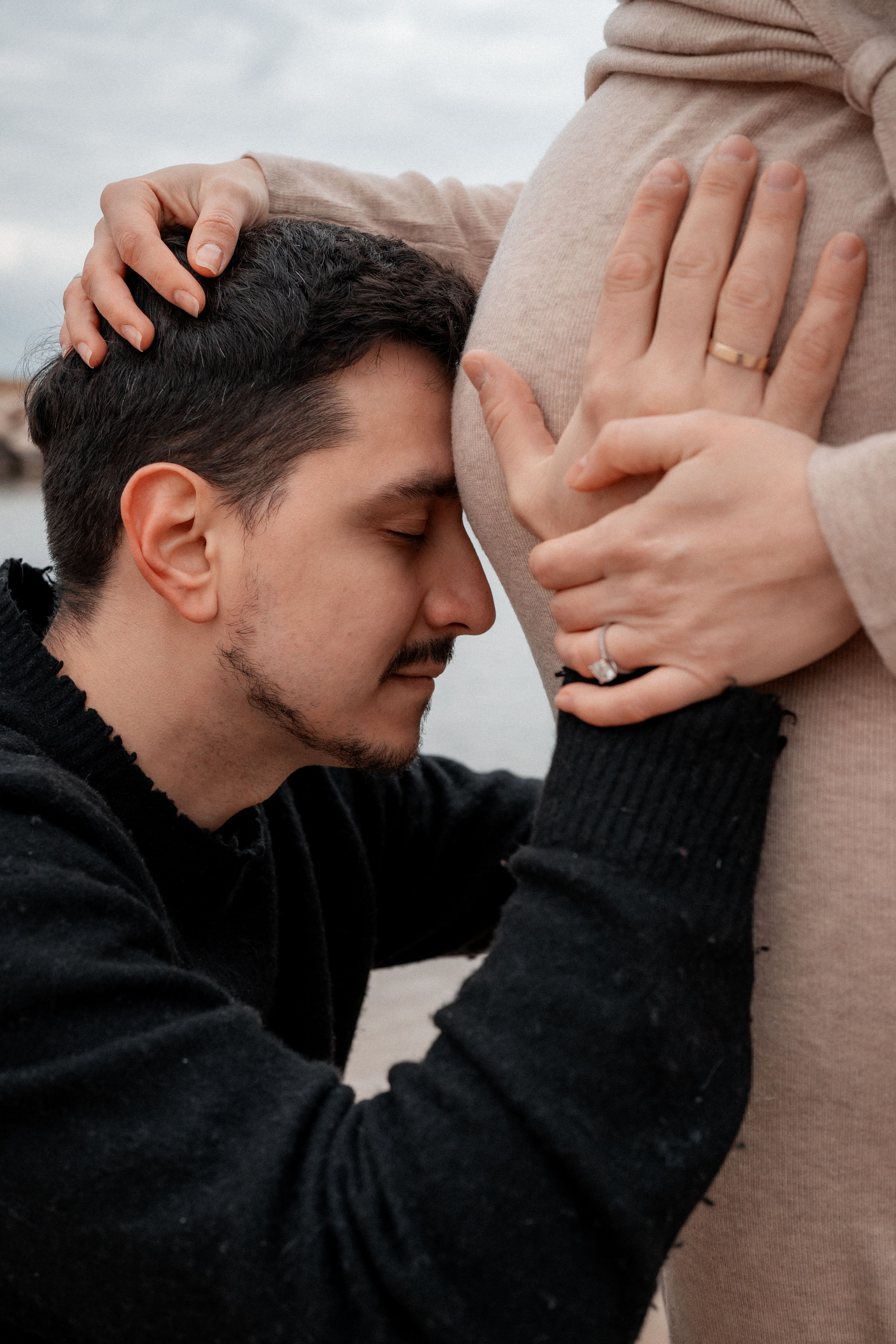 Expectant father gently embraces pregnant belly while showing intimate emotional connection.