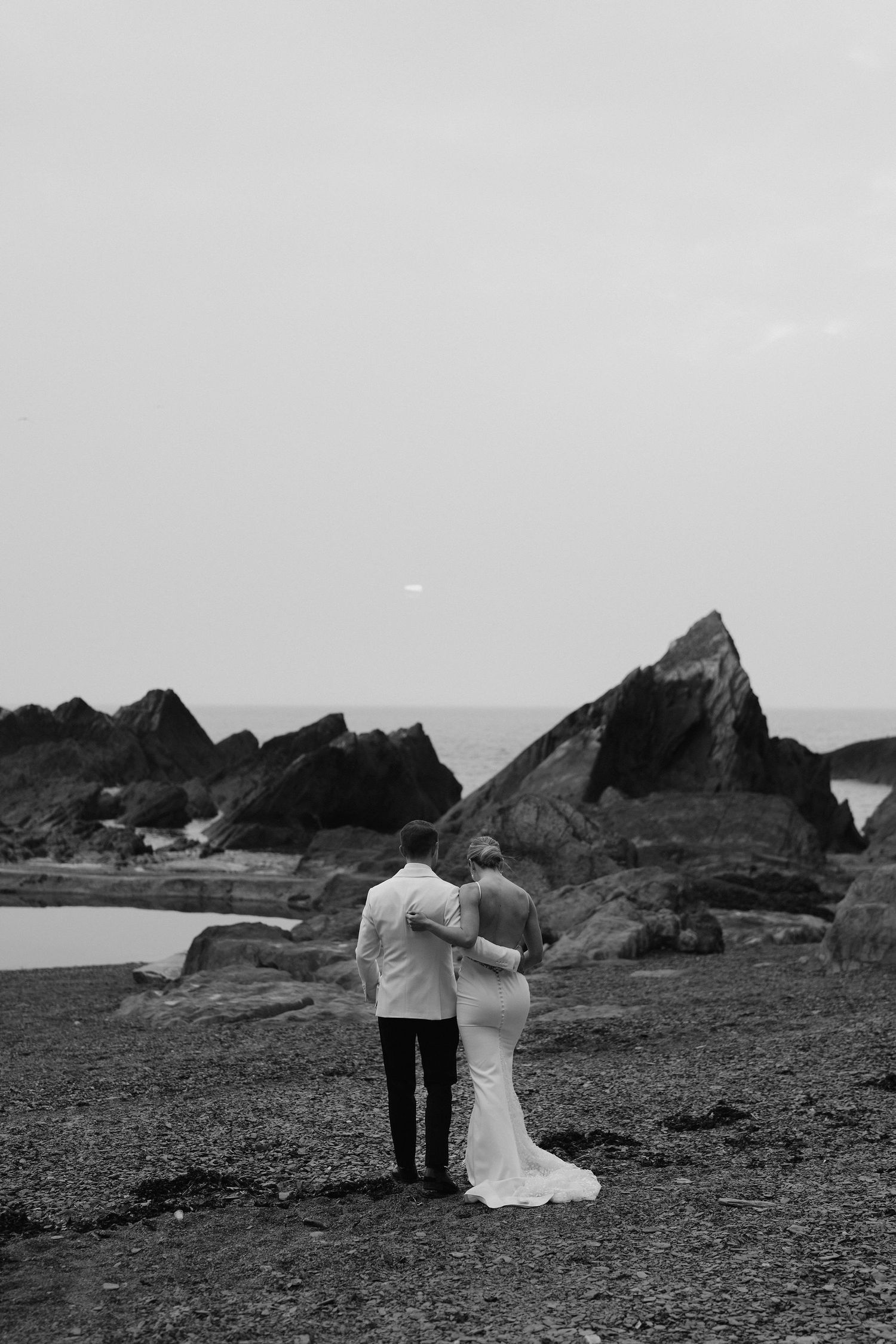 Bride and Groom walking along beach during sunset at tunnels beach wedding venue in north Devon