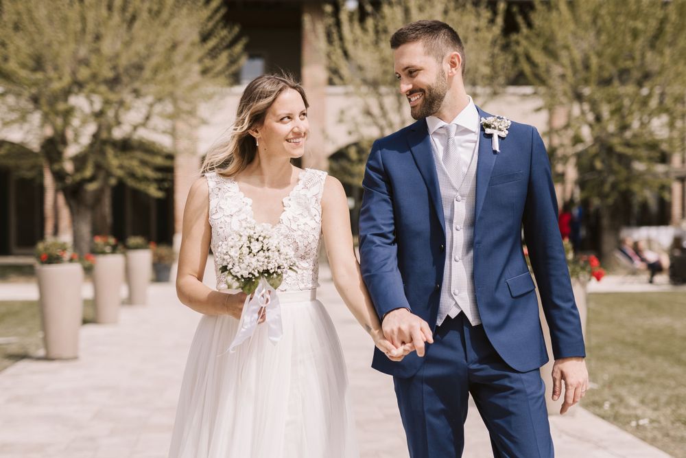 Sposo e sposa camminano tenendosi per mano e sorridendo uno all'altra