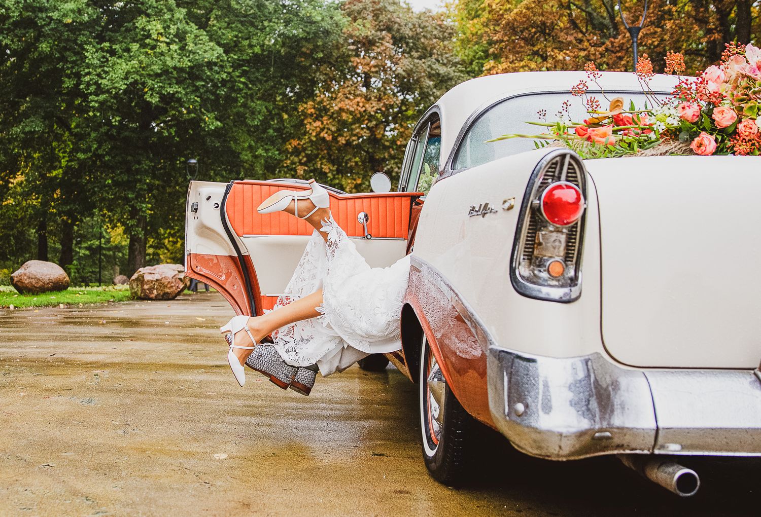 Vintage white car with decorative flowers parked in autumn setting. Bruidsfotografie Nederland.