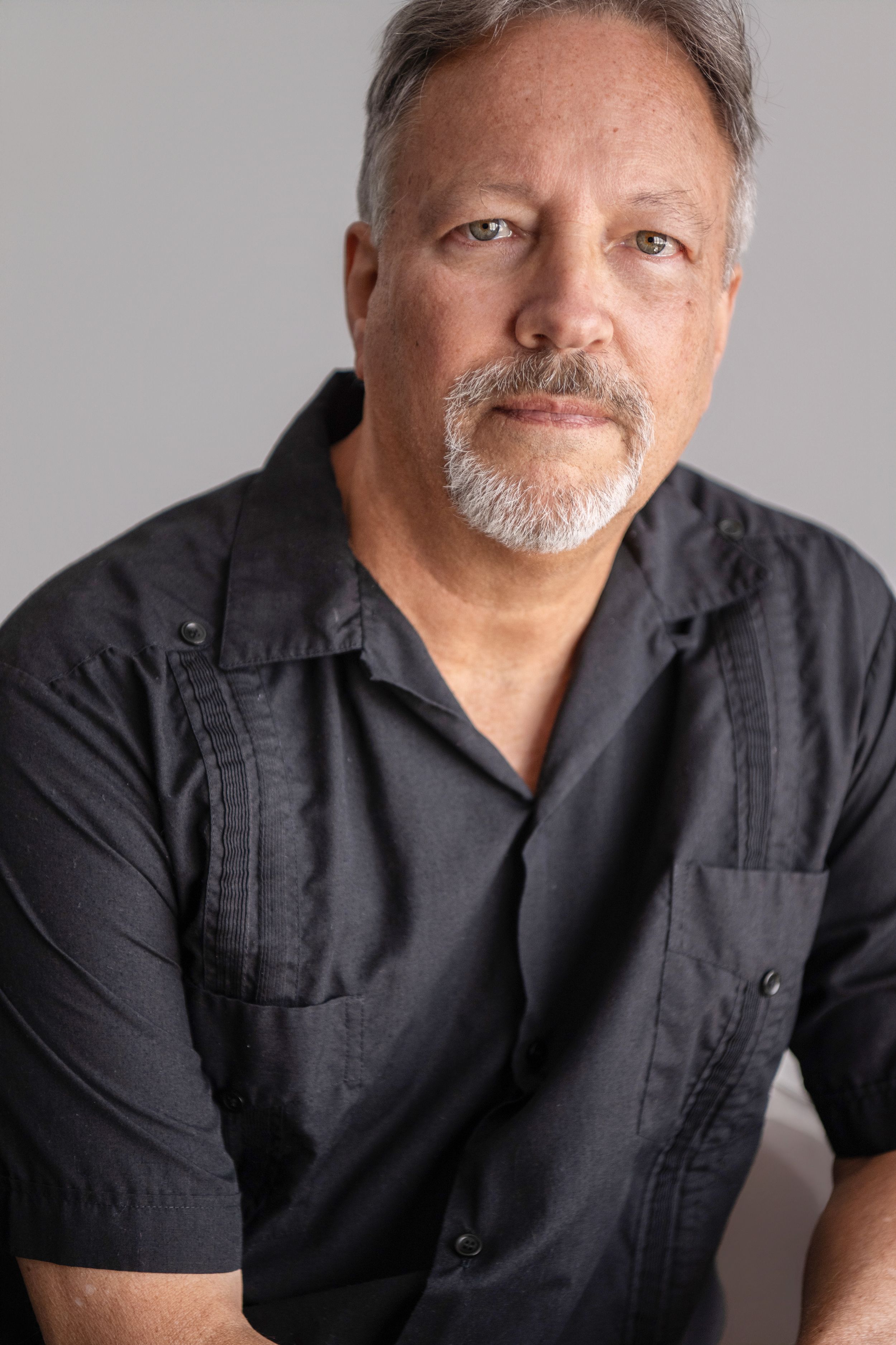 A series of professional headshot portraits showing a person wearing a black button-up shirt against a gray background.