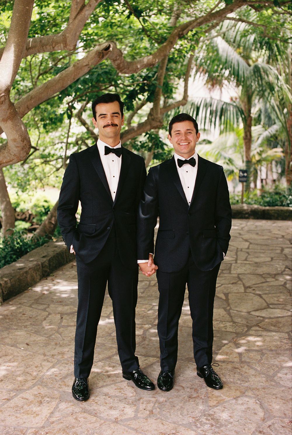 Two grooms smile for a film portrait for their wedding day at the Santa Barbara Courthouse.