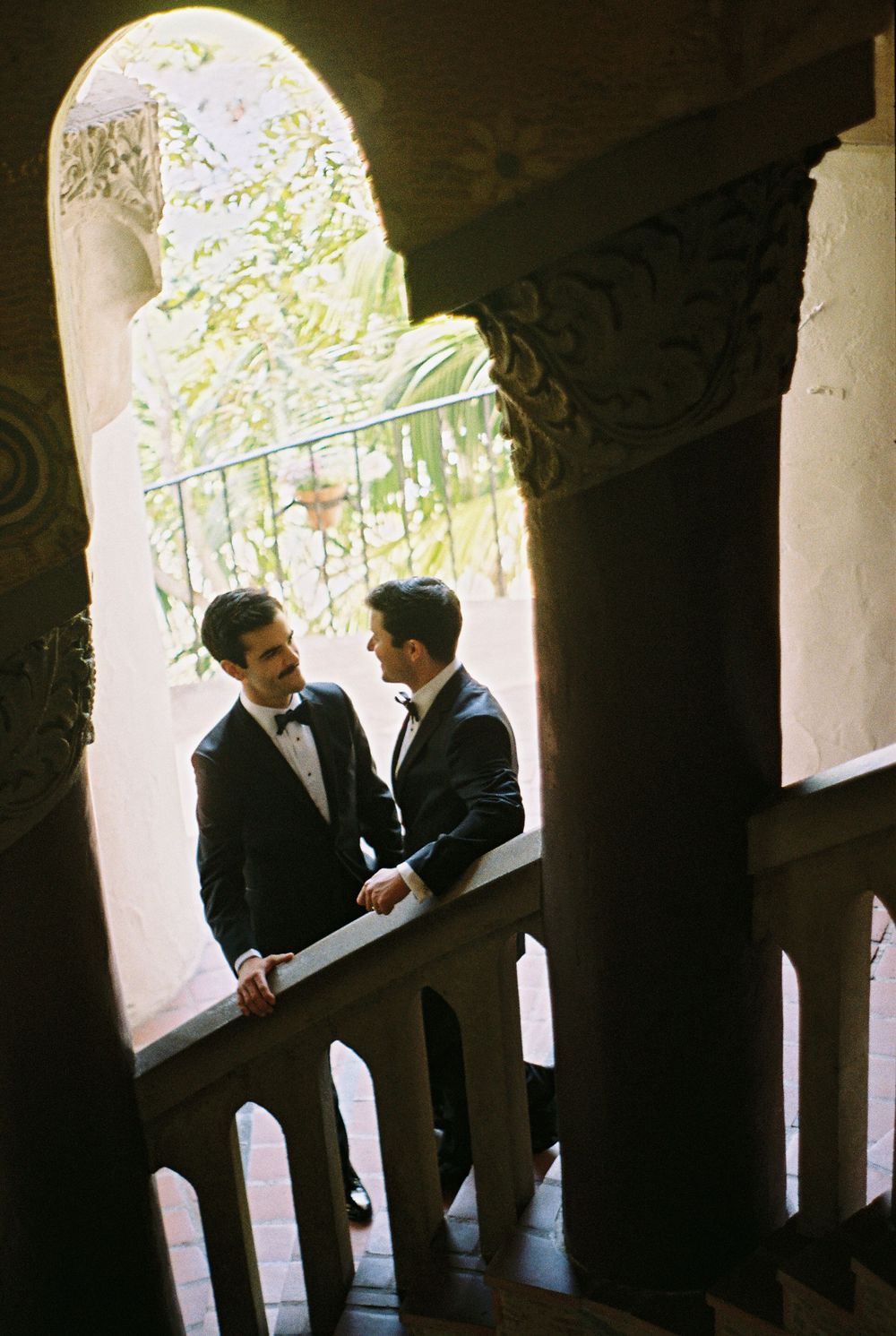 Same-sex couple holding hands on the iconic tiled staircase inside the historic Santa Barbara Courthouse.