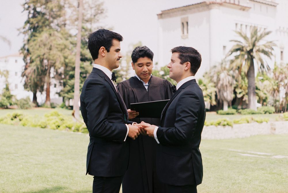Candid, documentary-style photo of a joyfully eloping same-sex couple shot on film at Santa Barbara Courthouse