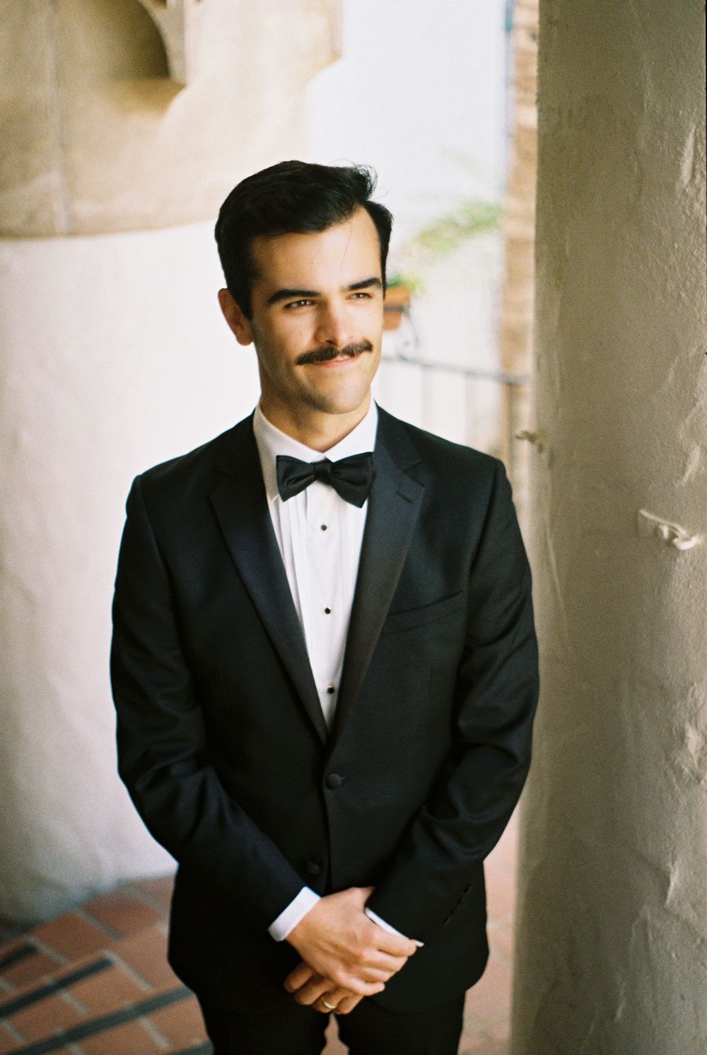 Editorial film wedding portrait of groom looking out over the city from the Santa Barbara Courthouse clock tower.