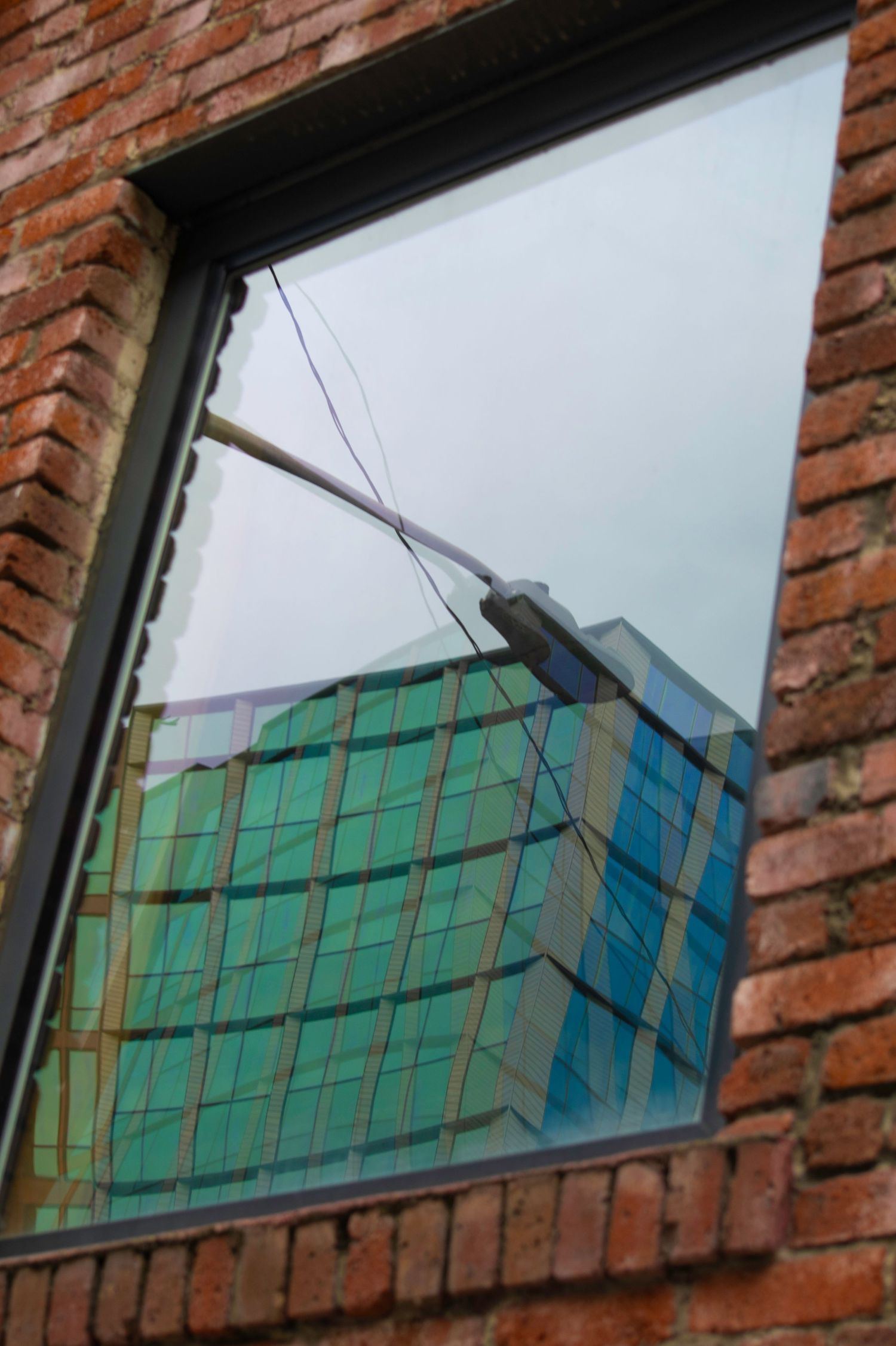 Reflection of a modern glass building in a brick wall window