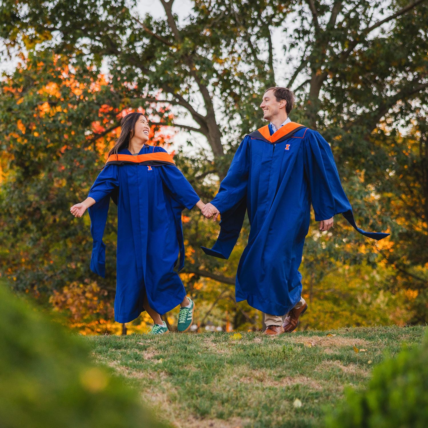 Graduating couple running together holding hands at Japan House at UIUC with masters graduation attire on