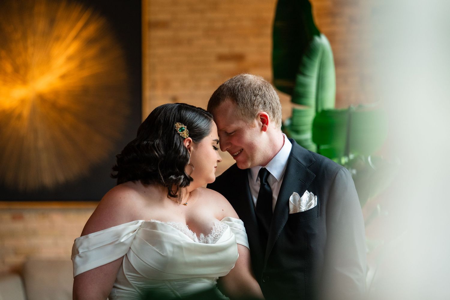 Bride and groom share an intimate moment, smiling at each other in elegant wedding attire at a modern venue.