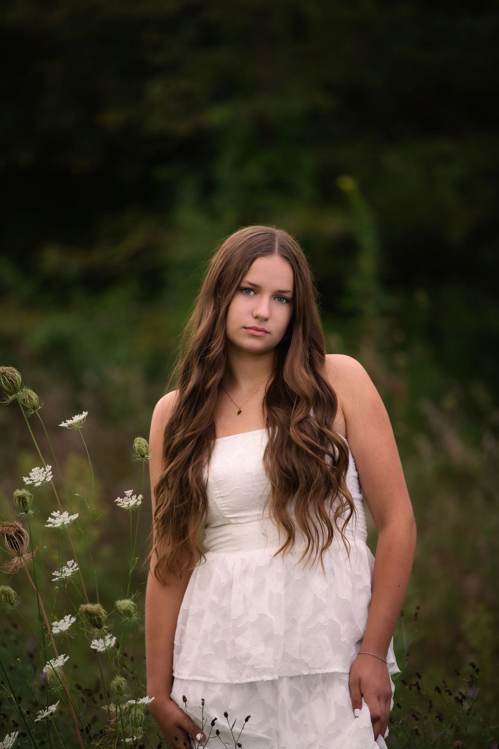 Senior portrait at Island Lake, Brighton Michigan; girl standing in flower field with cinematic aesthetic by South Lyon, MI photographer