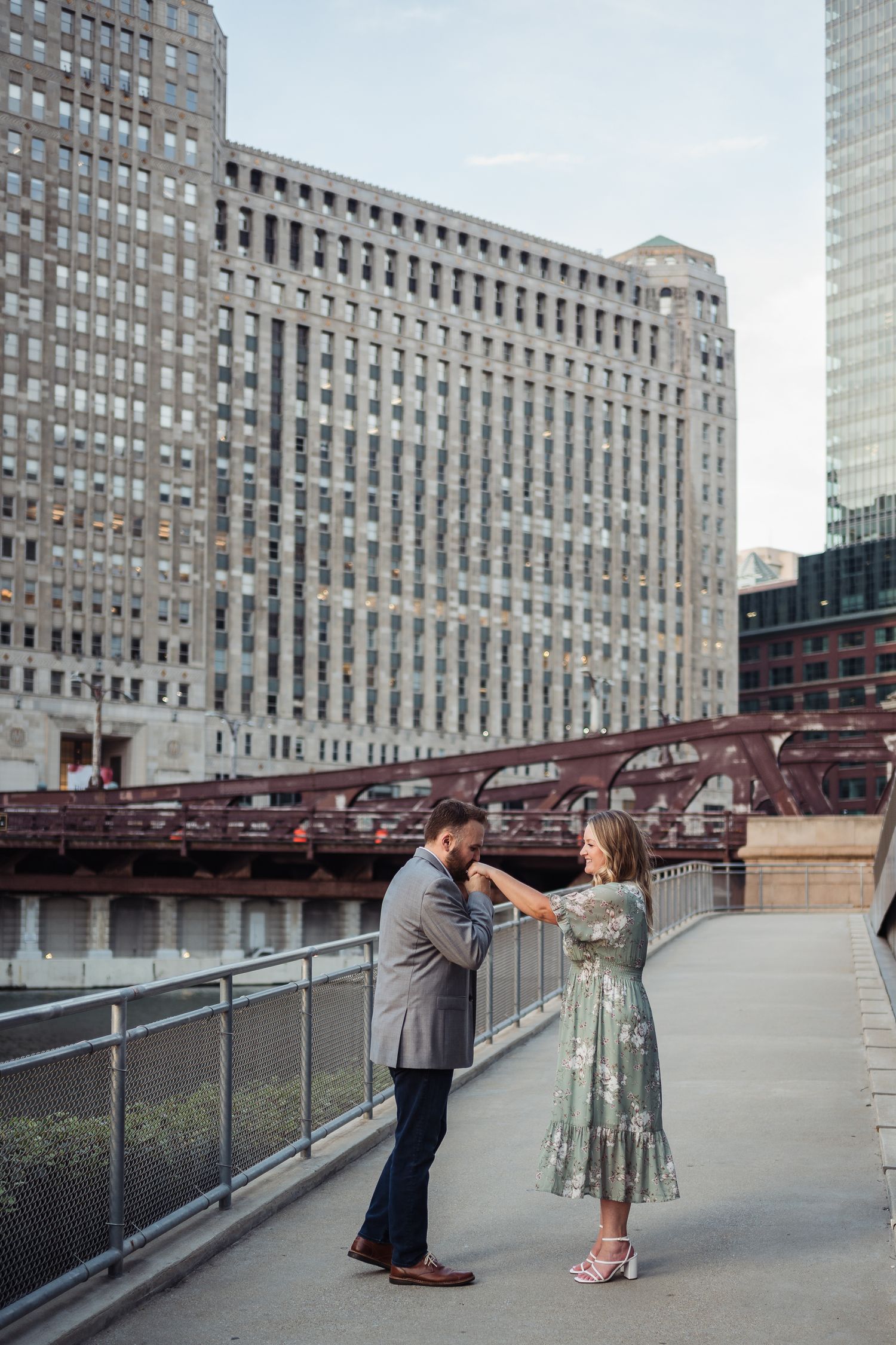 Couple dancing on a Chicago riverwalk bridge with city skyscrapers in the background.