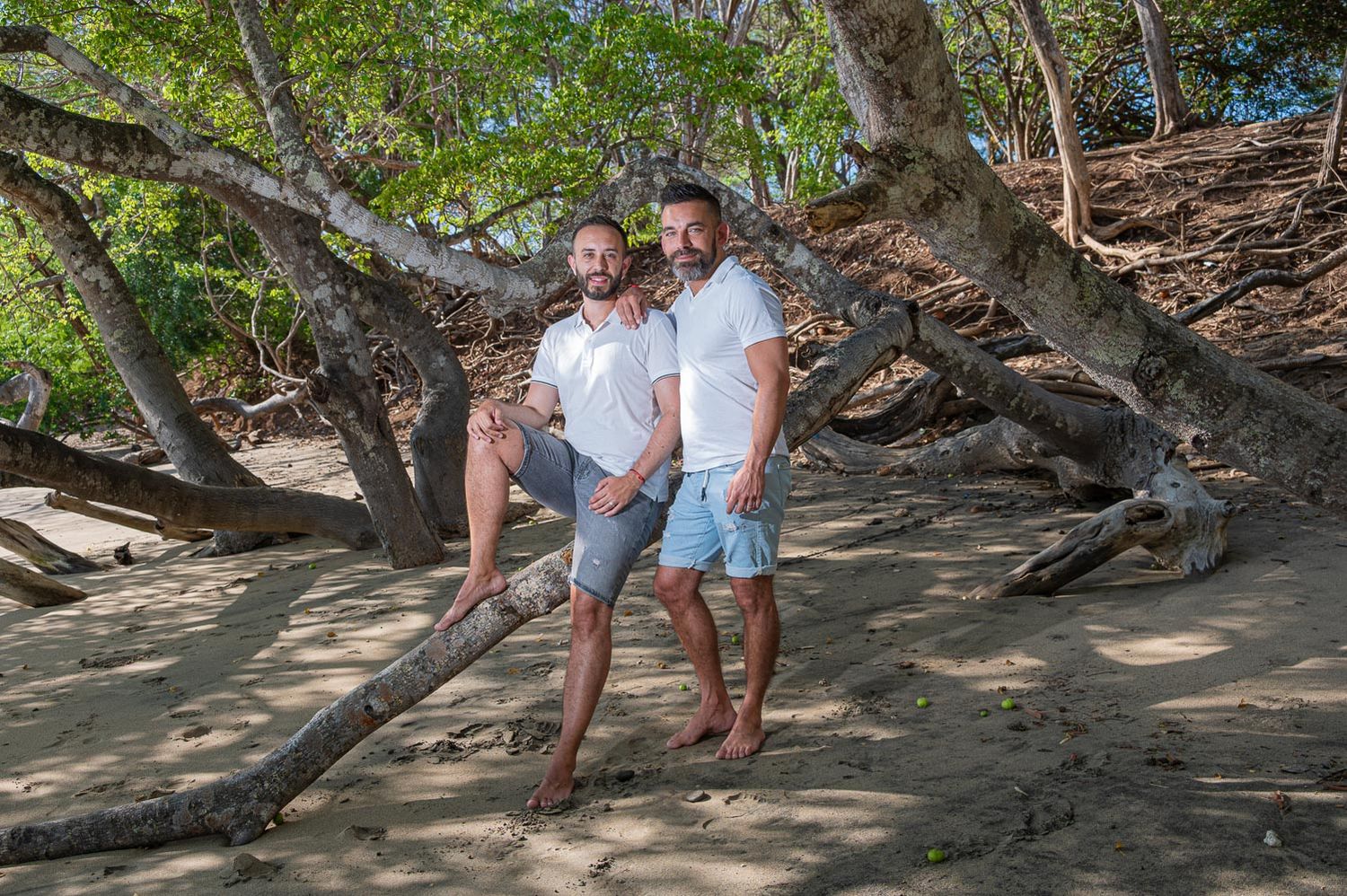 Couple embracing romantically on a sandy beach at sunset with calm ocean waves in the background.