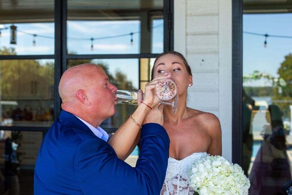 Bride and groom share a champagne toast together at their wedding reception outdoor venue.
