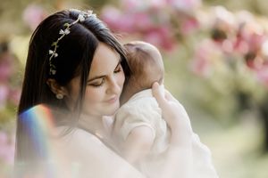 A tender moment captured in soft focus with someone holding a baby against a dreamy pink floral background.
