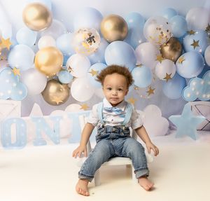 First birthday party setup with light blue and gold balloon arch backdrop and festive decorations.