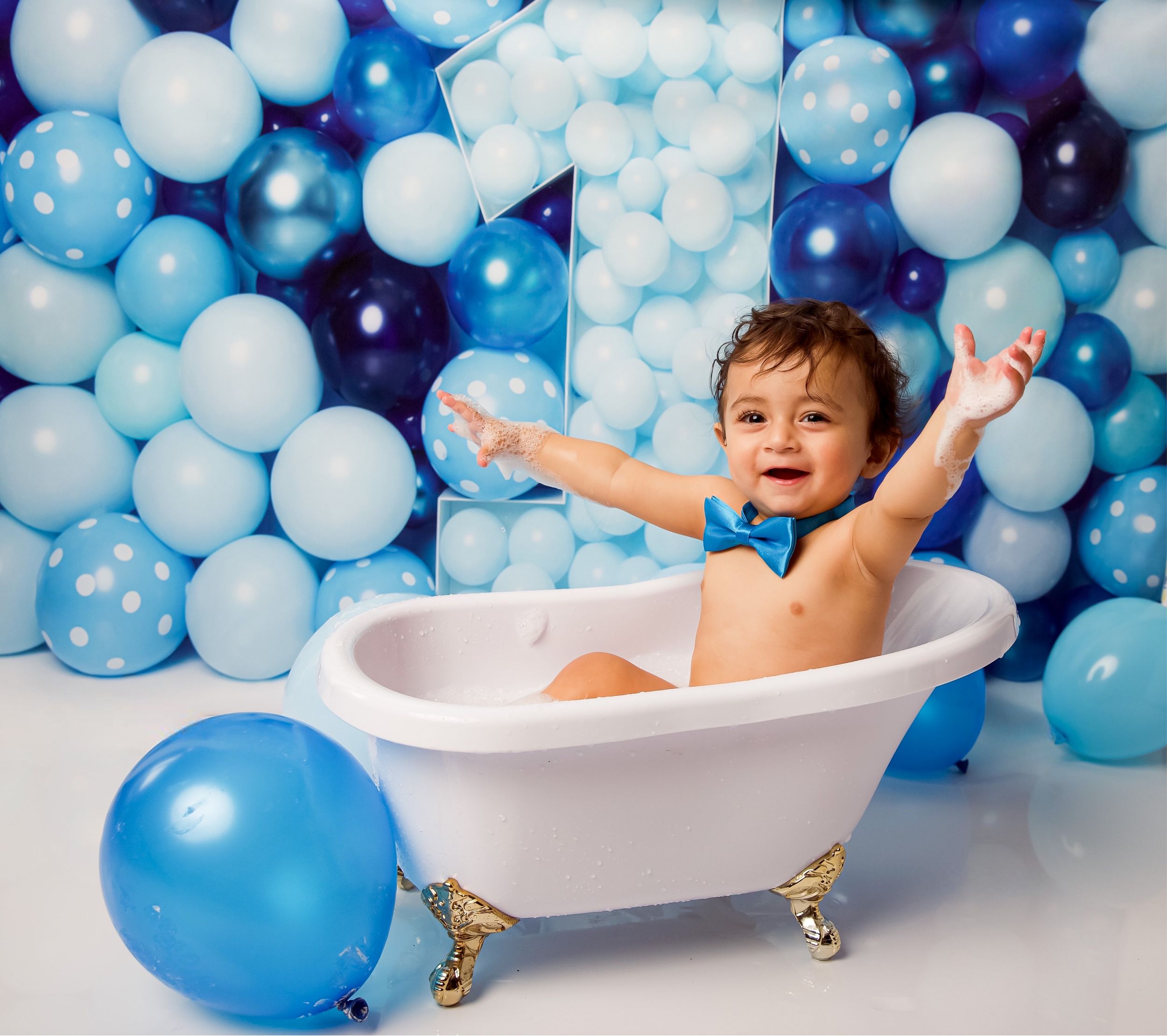 Playful bath time scene with blue and white balloon backdrop featuring a decorated clawfoot tub and joyful celebratory mood.