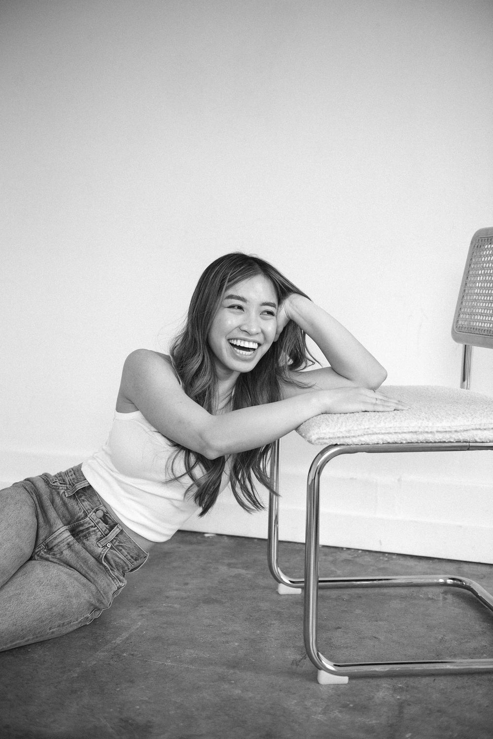 Person in casual attire lying playfully on modern furniture in black and white photography.