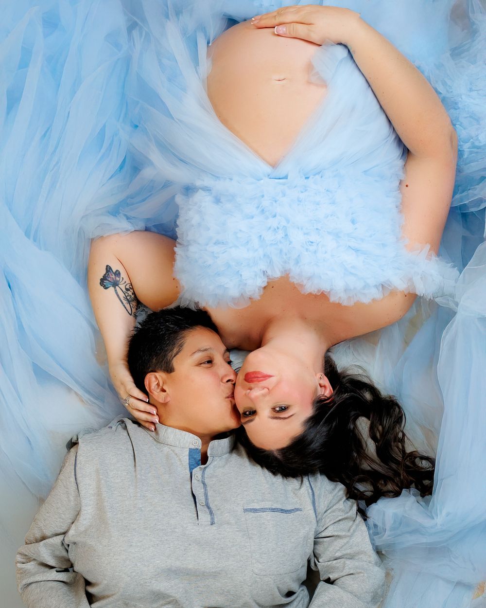 Two people in blue tulle fabric laying down together in an intimate pose.