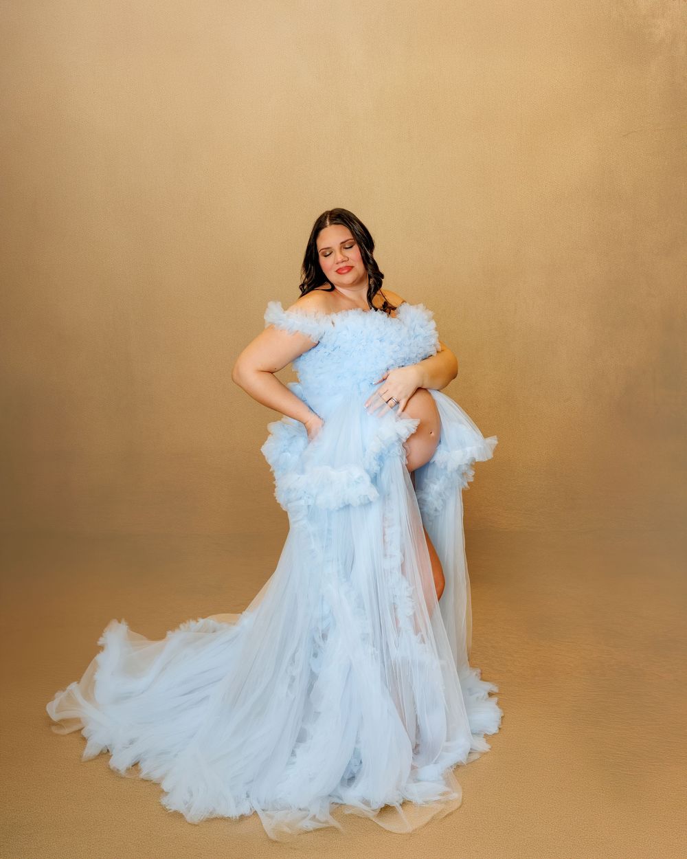 A figure in a flowing light blue tulle dress twirls gracefully against a warm beige backdrop.